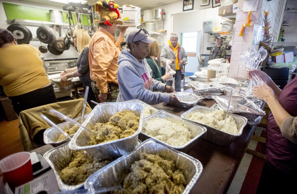 Image shows volunteers and staff preparing a meal in the kitchen at Our Community Place (OCP) in Harrisonburg, Virginia. Photograph by Daniel Lin from the Daily News-Record in Harrisonburg.